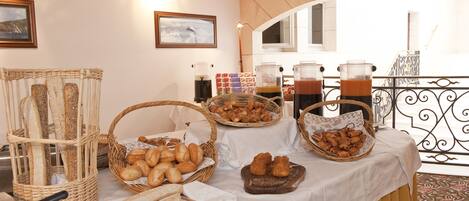 A buffet table with various breads and pastries, a knife, and a bowl of fruit.