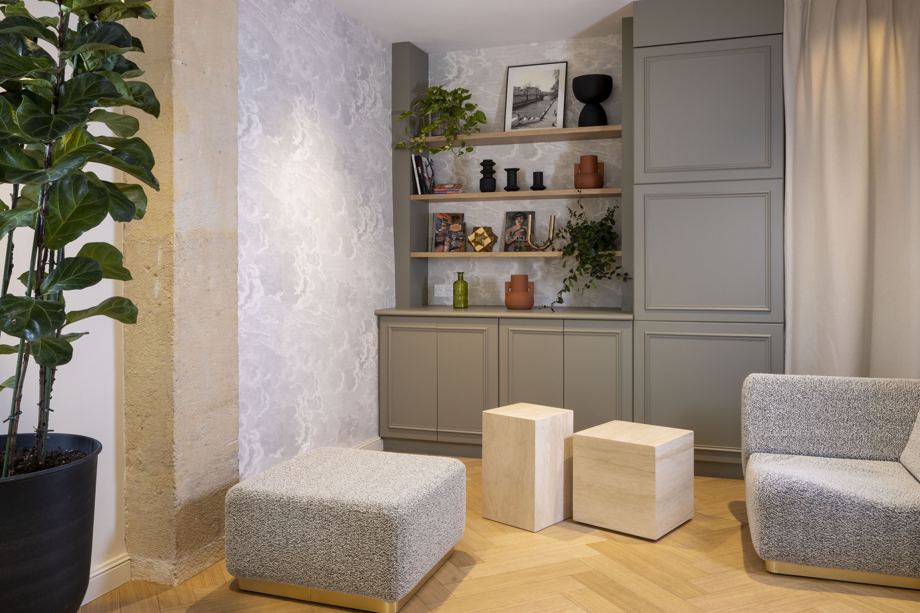 A modern living room with grey sofas, a wooden coffee table, and a bookshelf with decorative items.