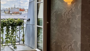 A room with a view of the cityscape, a window with a view of the sky, and a wall-mounted light fixture. - Abbatial Saint Germain (Paris)