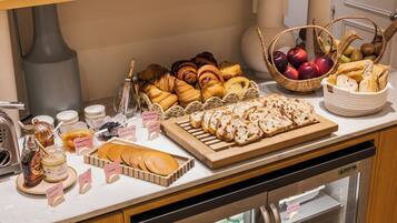A breakfast buffet with pastries, bread, and fruit baskets.
