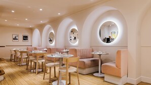 A modern interior with round tables, cushioned seating, and arched ceiling mirrors. - Hôtel Oratio (Paris)