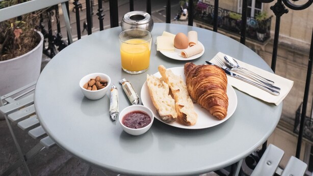 A round table with breakfast items on a balcony overlooking a cityscape. - Hôtel Oratio (Paris)