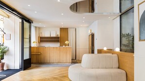 Een moderne hotel lobby met een receptiebalie, een zithoek en een groot raam.