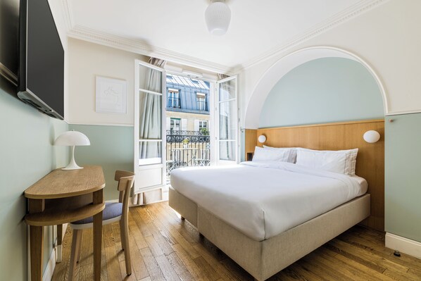 A bedroom with a bed, a desk, a chair, and a TV. - Hôtel Oratio (Paris)
