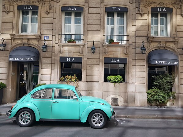 A classic turquoise vintage car parked in front of a building with multiple 'H.A' signs and 'HOTEL ALISON' signage. - Hôtel Alison (Paris)