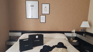 Una habitación de hotel con cama, mesita de noche, lámpara y cuadros en la pared.