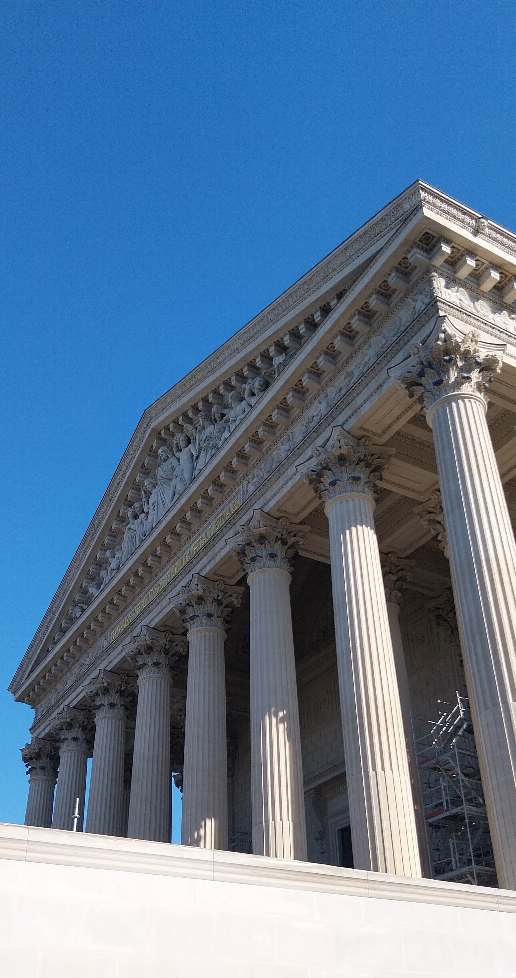 A neoclassical building with a grand facade, large columns, and detailed sculptures.