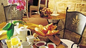 Desayuno con cruasanes, fruta y café en una habitación con paredes de piedra.
