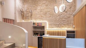 A modern interior with a stone wall, a wooden reception desk, and a wine display. - Hotel Arc Elysees (Paris)