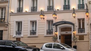 A multi-story hotel with a classic facade, multiple balconies, and a prominent entrance with illuminated signage. - Hotel Arc Elysees (Paris)