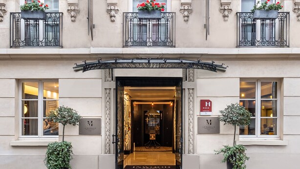 A multi-story hotel with a classic facade, featuring balconies with wrought iron railings, large windows, and decorative plant boxes. - Hôtel Le Marquis by Inwood Hotels (Paris)