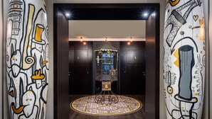 A lobby with a circular patterned floor, a central decorative structure, and walls with abstract designs. - Hôtel Le Marquis by Inwood Hotels (Paris)