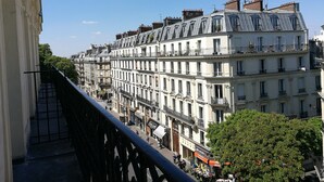 A row of multi-story buildings with balconies, a clear sky, and a pedestrian street below. - Hotel Claude Bernard Saint Germain (Paris)