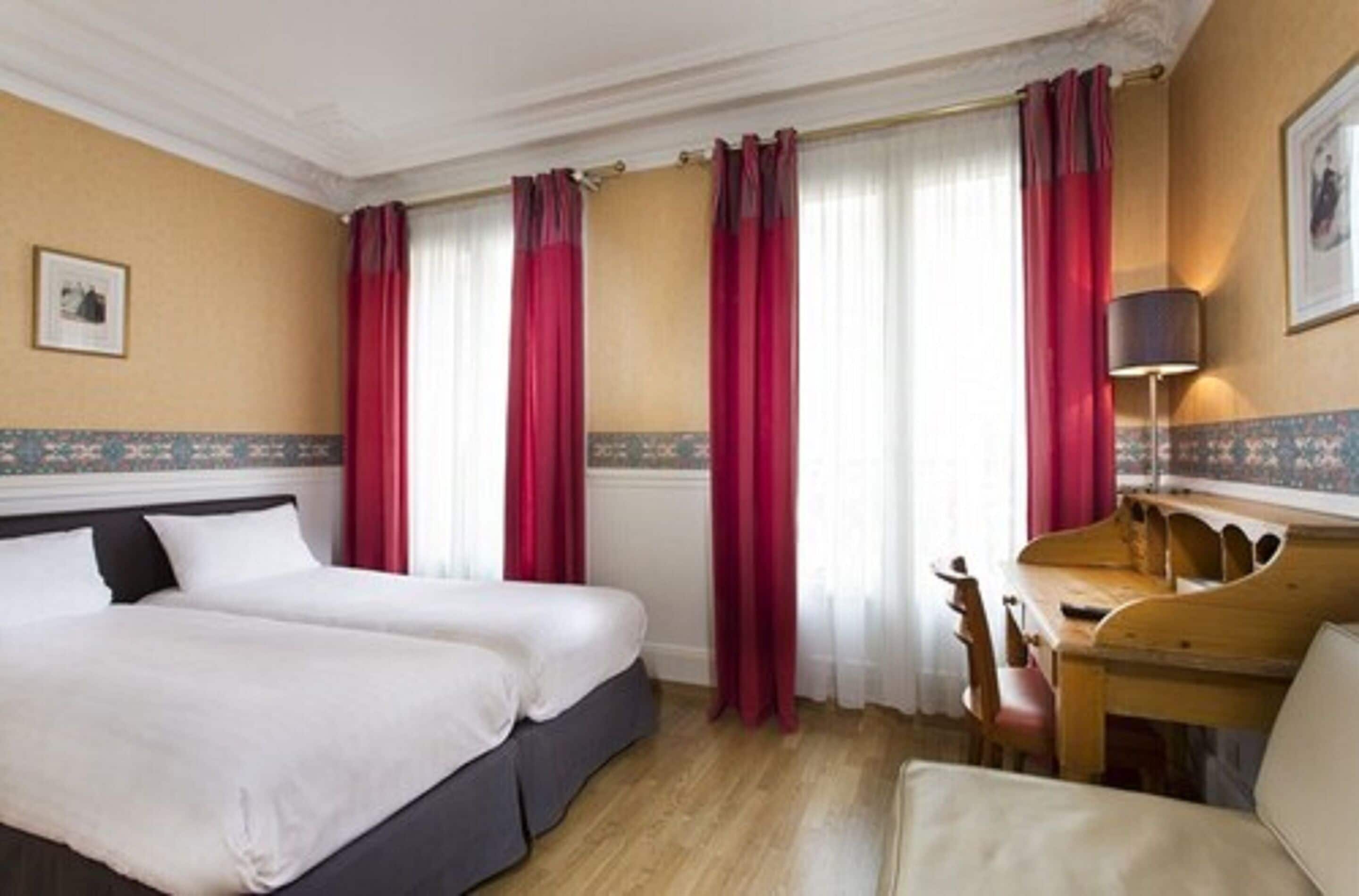 A hotel room with two beds, a desk, and a chair.