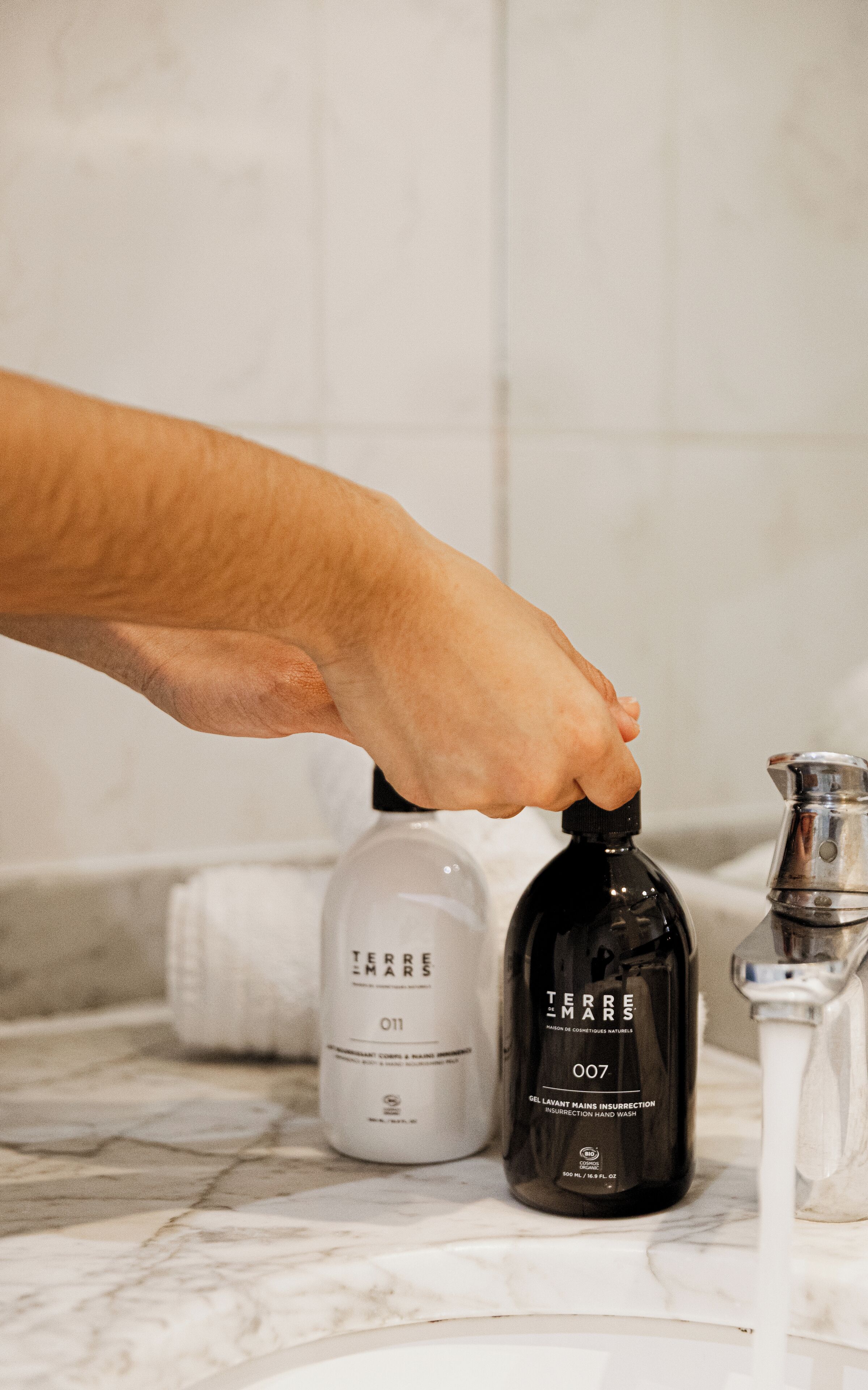 A hand dispensing water from a bottle into a sink.