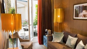 A modern living room with a sofa, a chair, a table, and two floor lamps. - Hôtel Baume (Paris)