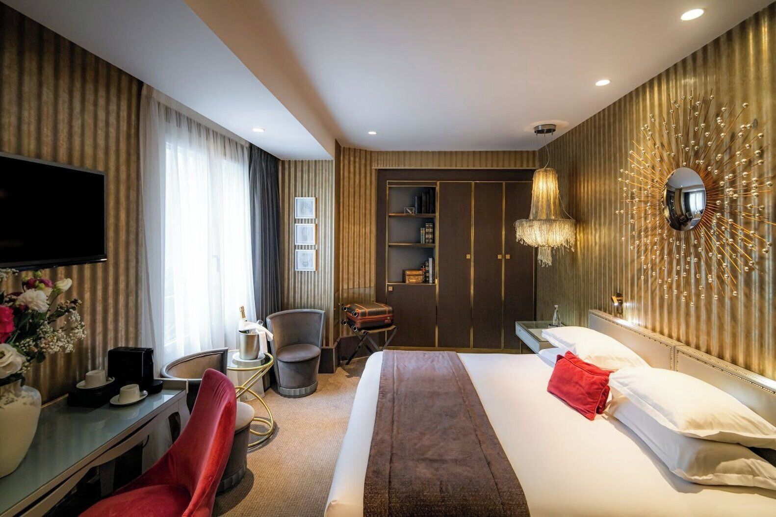 A hotel room with a bed, a desk, a chair, a television, and a wardrobe.
