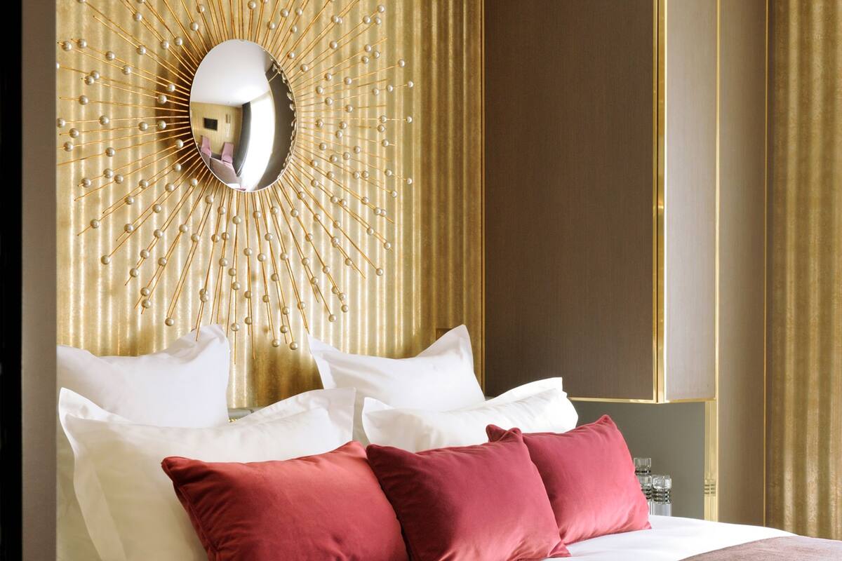 A hotel room with a large bed, a decorative wall panel, and a wardrobe.