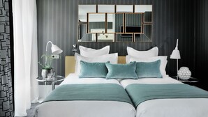 A modern hotel room with a large bed, a mirror with geometric frames, a bedside table with a lamp, and a decorative sphere. - Hôtel Baume (Paris)