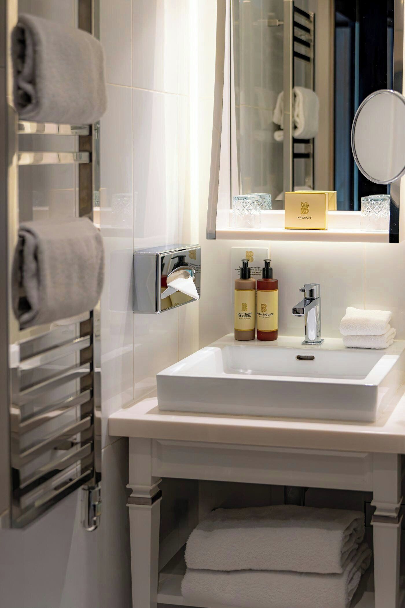 A hotel bathroom with a white sink, a towel rack, and toiletries.