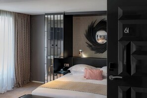 Une chambre d’hôtel moderne équipée d’un lit, d’une table de chevet, d’un miroir et d’une porte portant un numéro.