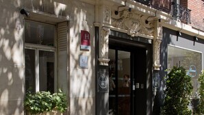Entrada de un hotel con un letrero rojo en forma de 'H', una placa y un cartel que dice 'Chouette Hotel'.