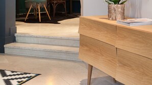 Un interior moderno con zona de comedor, una consola de madera y una orquídea en maceta.