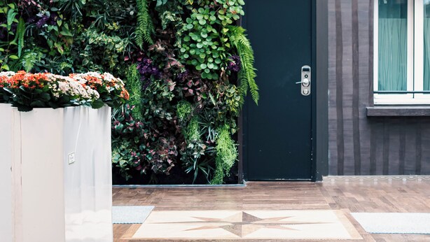 A reception area with a vertical garden, a dark door, and hanging lamps. - Hotel Aida Marais Printania (Paris)