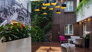 A modern lobby with a large mural, indoor plants, and a star-patterned floor. - Hotel Aida Marais Printania (Paris)