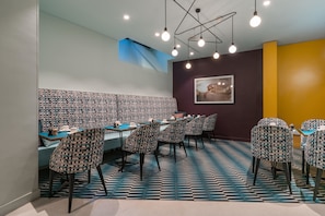 A restaurant with patterned chairs and tables, a blue and white tiled floor, and a ceiling with hanging lights. - Hôtel Artus (Paris)