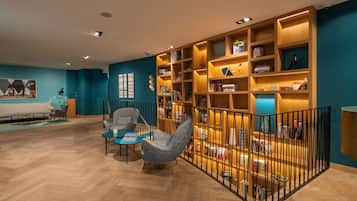 Una biblioteca moderna con estanterías de madera, una zona de estar confortable y un suelo con estampado de espiga.
