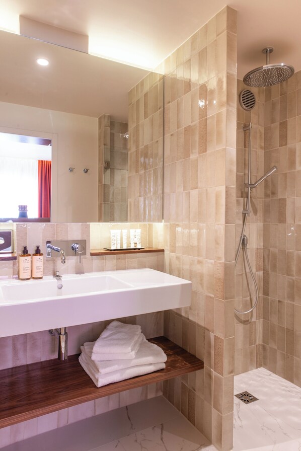 Une salle de bain moderne avec un grand lavabo, un miroir et une douche.