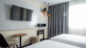 A hotel room with two beds, a TV, a small table, a chair, and a lamp. - Mercure Paris Montparnasse Pasteur (Paris)