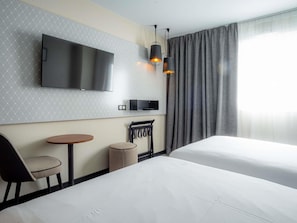A hotel room with two beds, a TV, a small table, a chair, and a lamp. - Mercure Paris Montparnasse Pasteur (Paris)