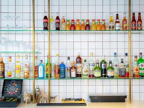 A bar area with shelves of various liquor bottles and glasses. - Mercure Paris Montparnasse Pasteur (Paris)