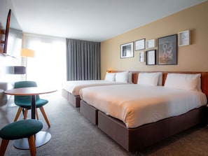 A hotel room with two beds, a small round table, a chair, and a lamp. - Mercure Paris Montparnasse Pasteur (Paris)