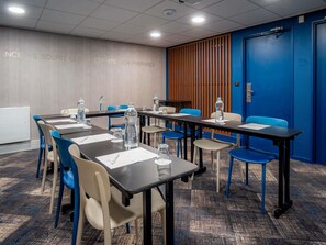 A conference room with tables and chairs, a whiteboard, and a blue wall with a vertical wooden panel. - Mercure Paris Montparnasse Pasteur (Paris)