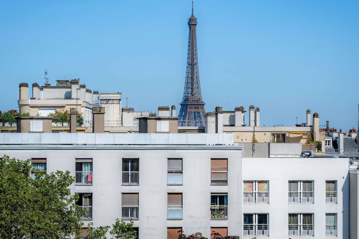 A high-rise building with multiple balconies and a clear view of the Eiffel Tower in the background.