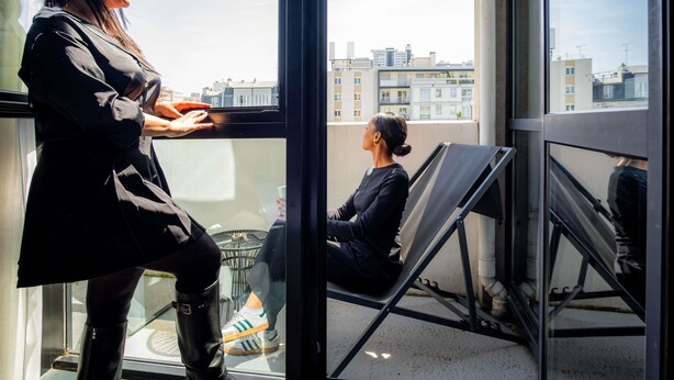 A person standing by a window with a view of buildings and a chair outside. - Mercure Paris Montparnasse Pasteur (Paris)