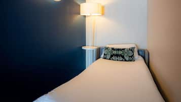 Et hotelværelse med en seng, en sengetavlelampe og en lampe på væggen.