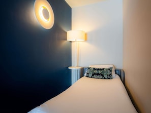 A hotel room with a bed, a bedside lamp, and a wall-mounted light fixture. - Mercure Paris Montparnasse Pasteur (Paris)