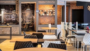 A modern cafe with exposed brick walls, round tables, and black and white cushioned chairs. - ibis Styles Paris Gare de l'Est Château Landon (Paris)