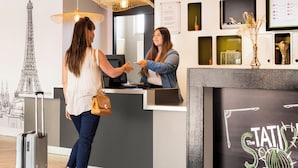 A reception desk with a chalkboard displaying "The Statue of Liberty" and a framed Eiffel Tower illustration. - ibis Styles Paris Gare de l'Est Château Landon (Paris)