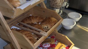 Paneras de madera con diversos tipos de pan y pasteles, incluyendo cruasanes y barras de pan.
