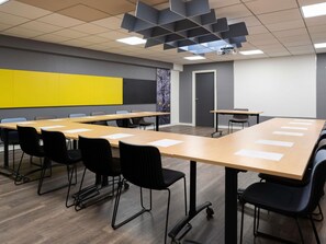 Una sala de conferencias con una larga mesa, sillas, un proyector y una pared de acento amarilla.