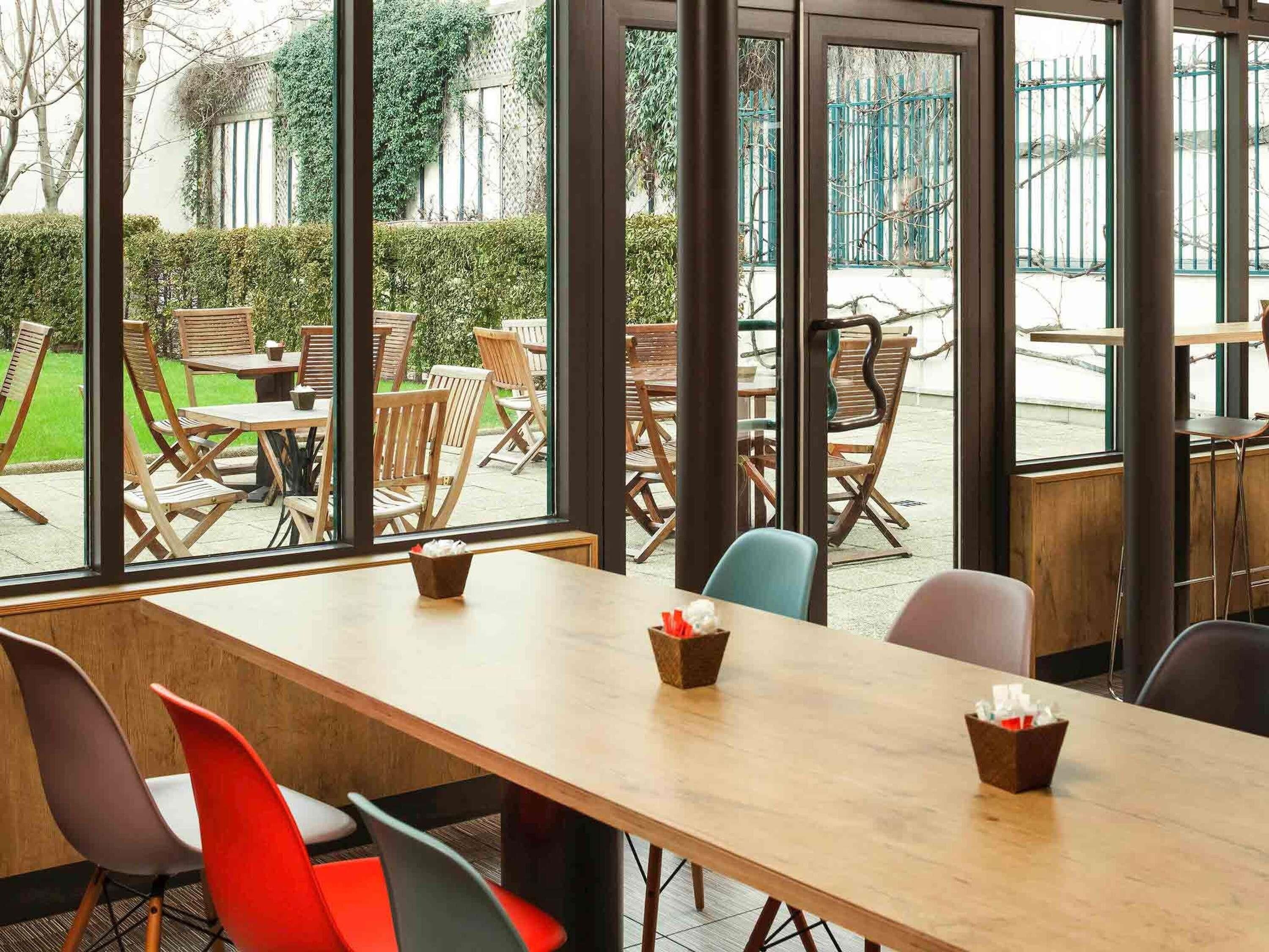 Un comedor interior moderno con amplias ventanas, mesas y sillas de madera.