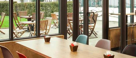 Un comedor interior moderno con amplias ventanas, mesas y sillas de madera.