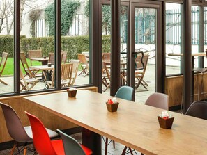Un comedor interior moderno con amplias ventanas, mesas y sillas de madera.