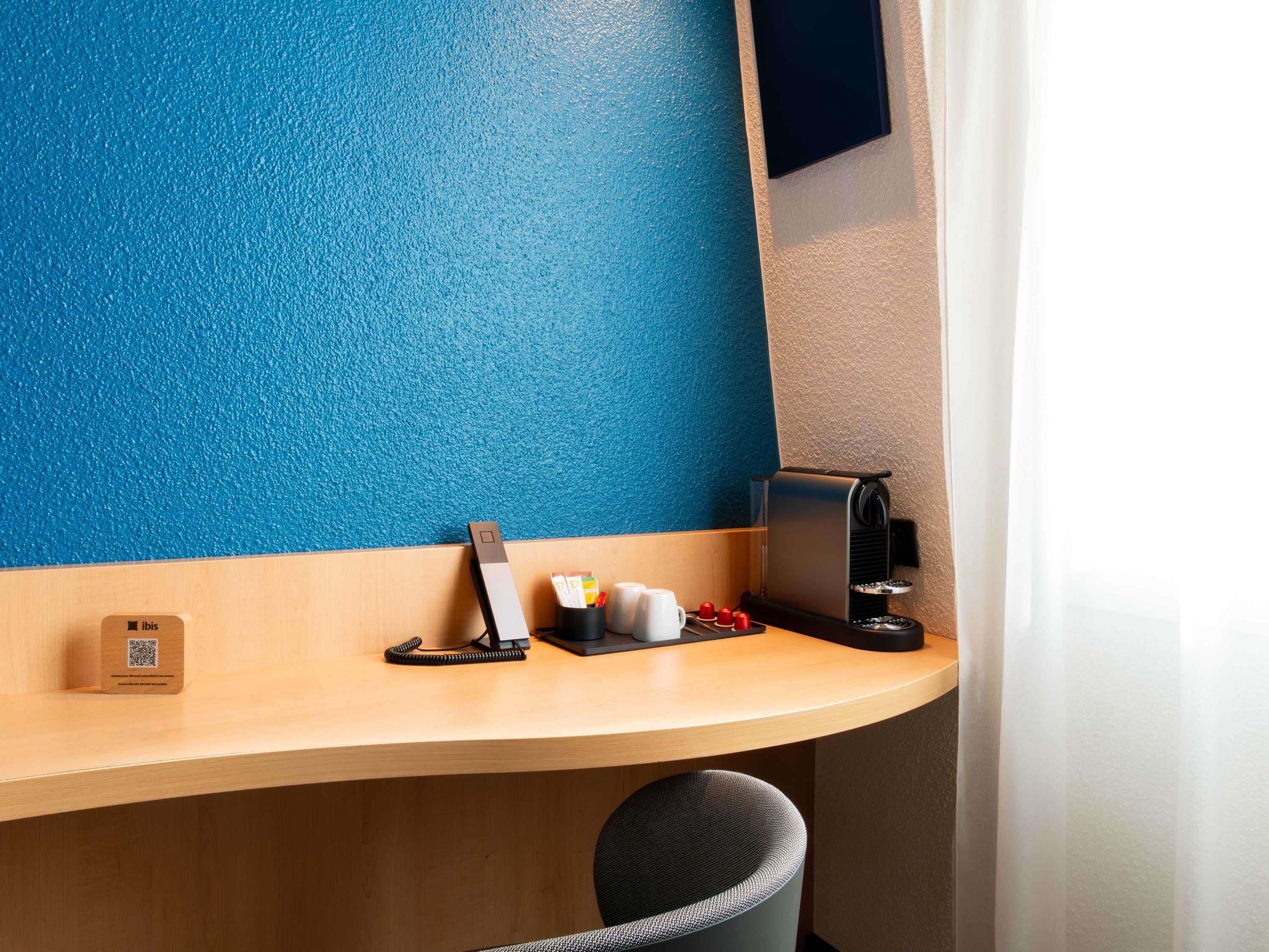 Une chambre d’hôtel avec un bureau en bois, une machine à café, un téléphone et une chaise.
