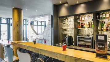 Una zona de bar con mostrador de madera, taburetes y una pared con diseño de pizarra.